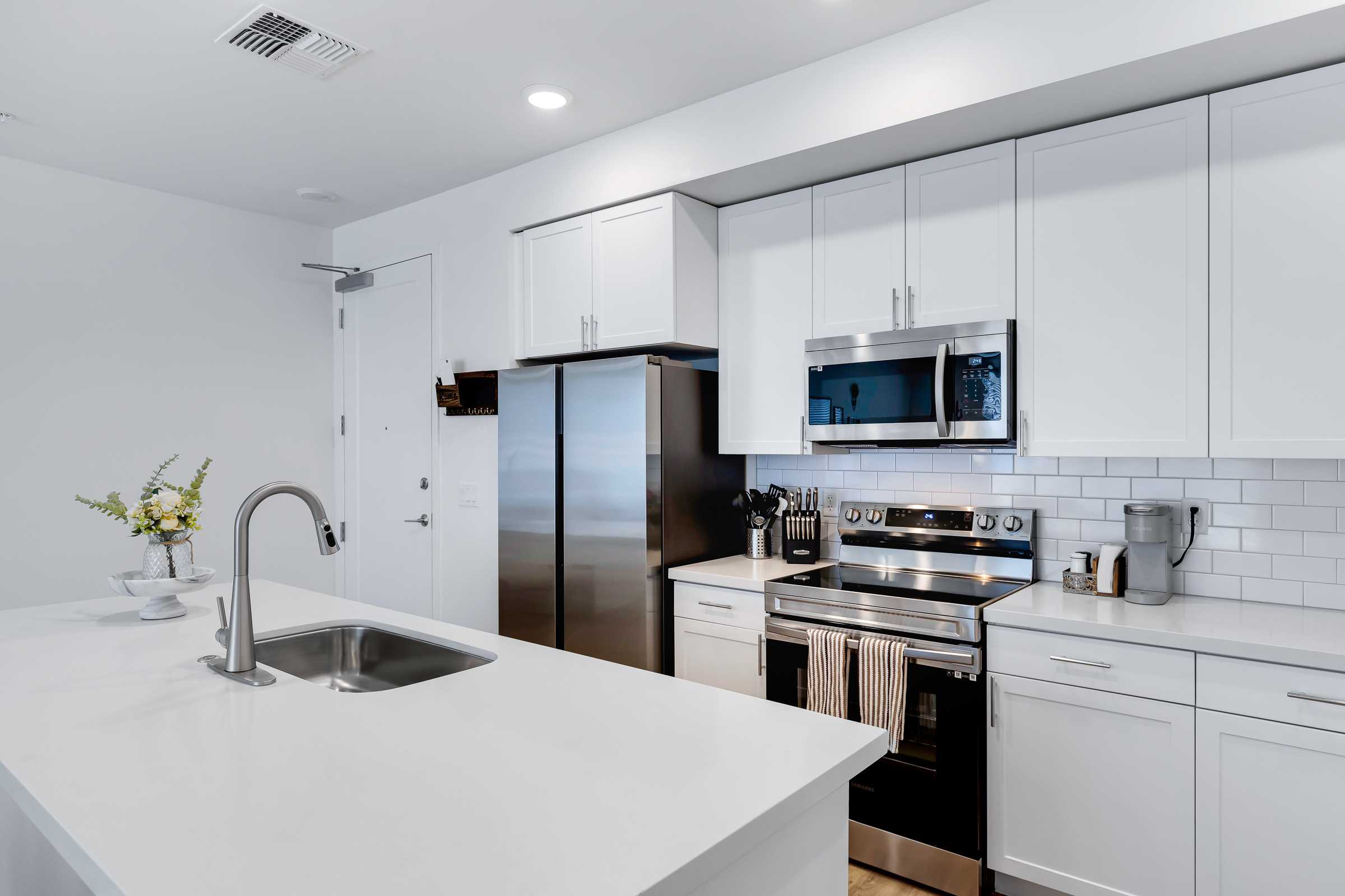 Bright kitchen with white cabinets, stainless steel appliances, and a center island